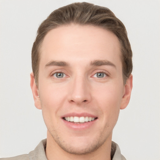 Joyful white young-adult male with short  brown hair and grey eyes