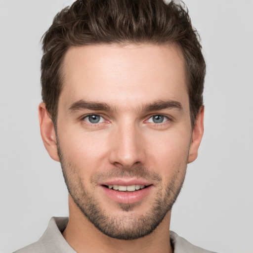 Joyful white young-adult male with short  brown hair and grey eyes