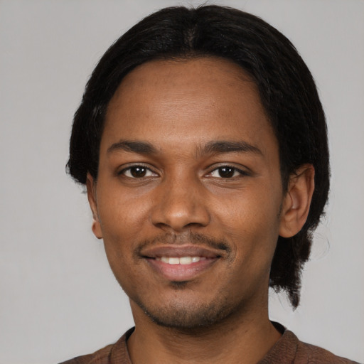 Joyful black young-adult male with short  black hair and brown eyes