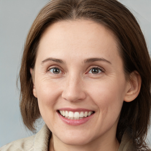 Joyful white young-adult female with medium  brown hair and grey eyes