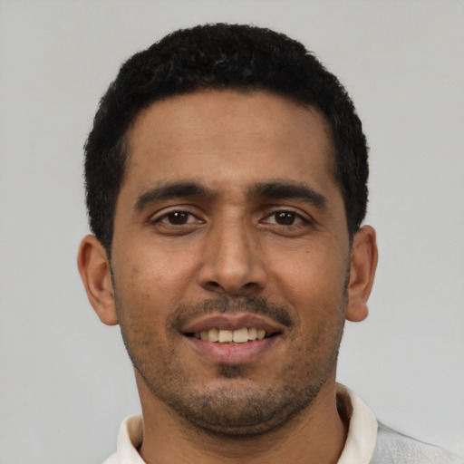 Joyful latino young-adult male with short  black hair and brown eyes