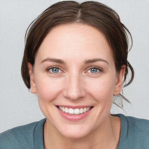 Joyful white young-adult female with medium  brown hair and grey eyes