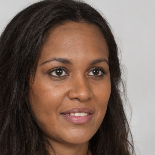 Joyful black young-adult female with long  brown hair and brown eyes