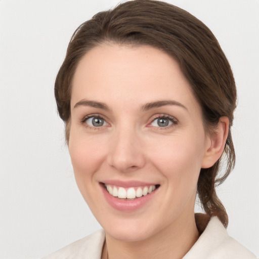 Joyful white young-adult female with medium  brown hair and grey eyes