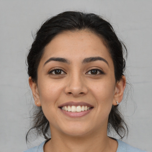 Joyful latino young-adult female with medium  brown hair and brown eyes
