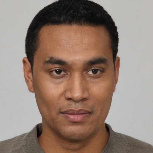 Joyful black young-adult male with short  black hair and brown eyes