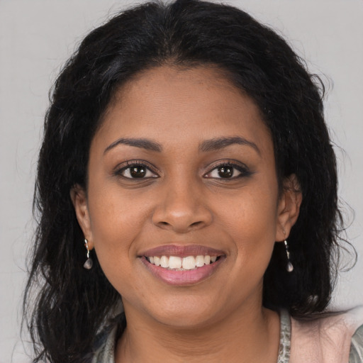 Joyful black young-adult female with long  brown hair and brown eyes