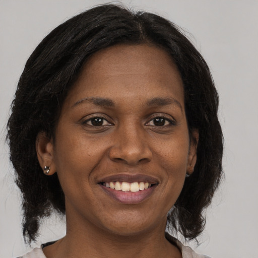 Joyful black adult female with medium  brown hair and brown eyes