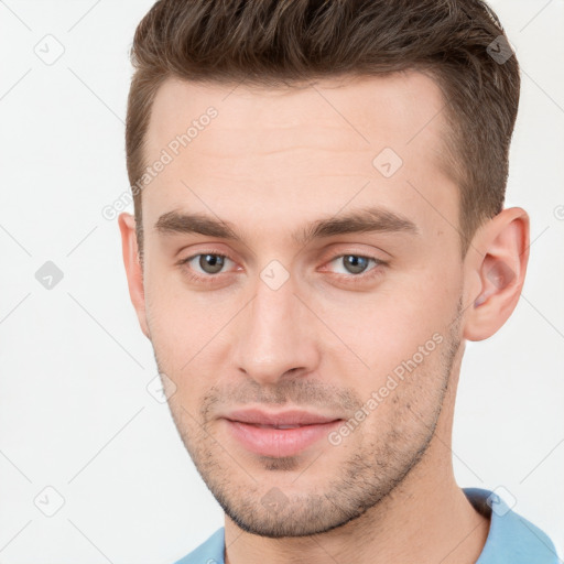 Joyful white young-adult male with short  brown hair and grey eyes