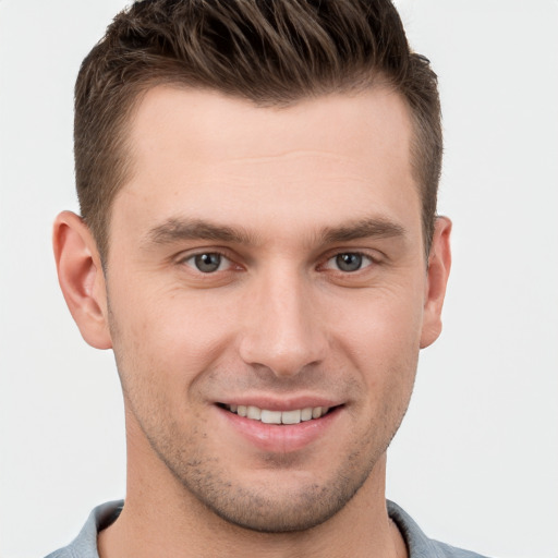 Joyful white young-adult male with short  brown hair and grey eyes