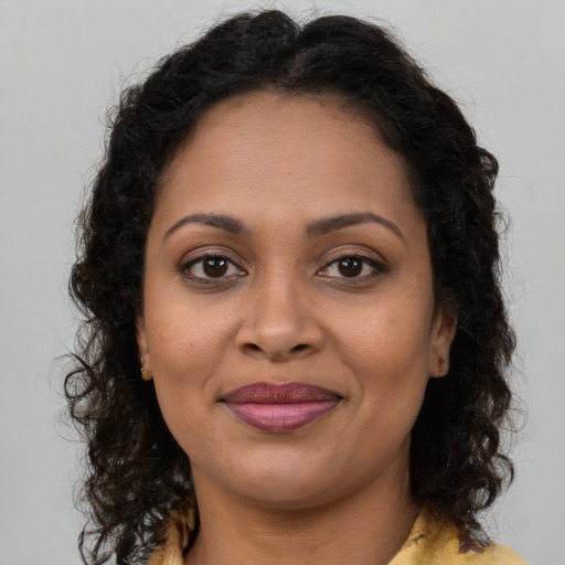 Joyful black young-adult female with long  brown hair and brown eyes