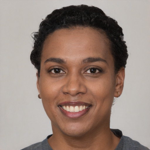 Joyful black young-adult female with short  black hair and brown eyes