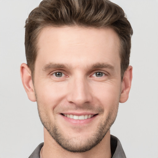 Joyful white young-adult male with short  brown hair and grey eyes