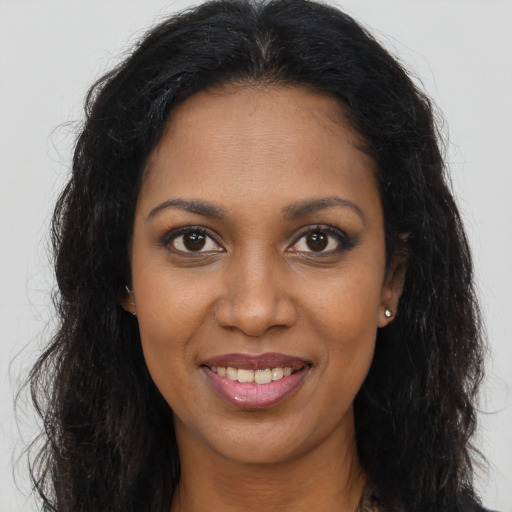 Joyful black young-adult female with long  brown hair and brown eyes
