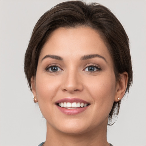 Joyful white young-adult female with medium  brown hair and grey eyes