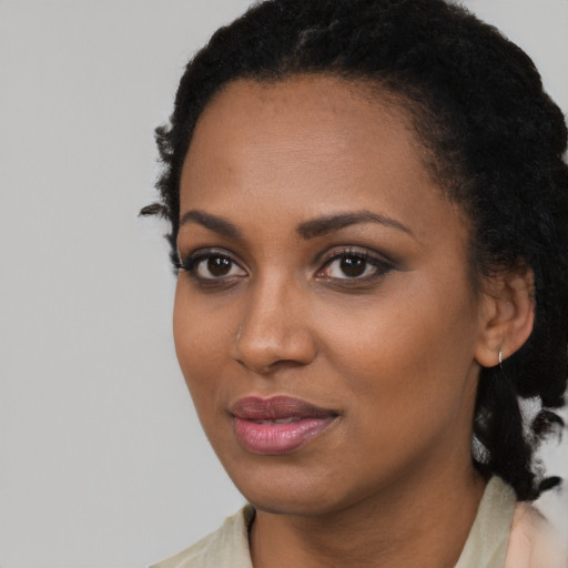 Joyful black young-adult female with long  black hair and brown eyes
