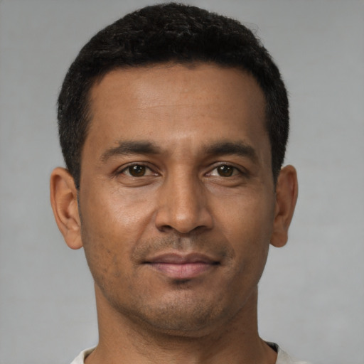 Joyful latino young-adult male with short  brown hair and brown eyes