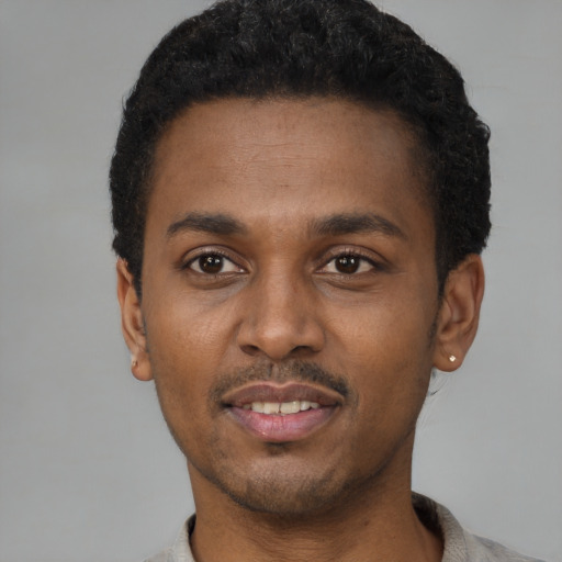 Joyful black young-adult male with short  black hair and brown eyes