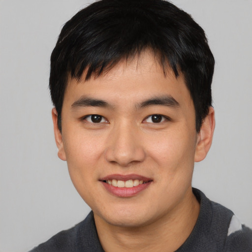 Joyful asian young-adult male with short  black hair and brown eyes