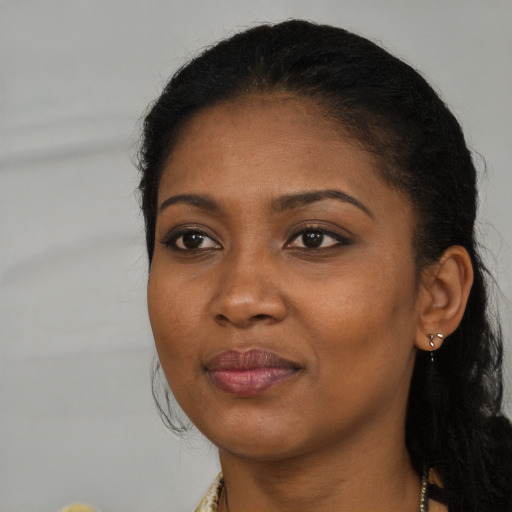 Joyful black young-adult female with long  black hair and brown eyes