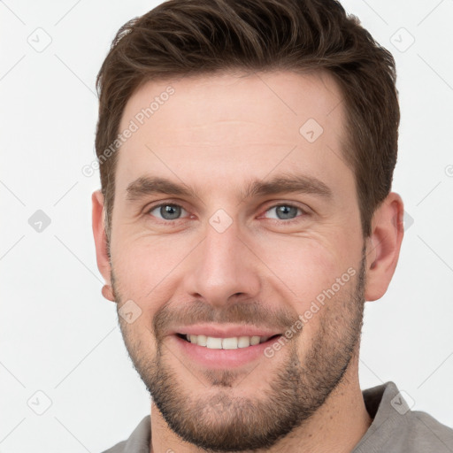 Joyful white young-adult male with short  brown hair and grey eyes