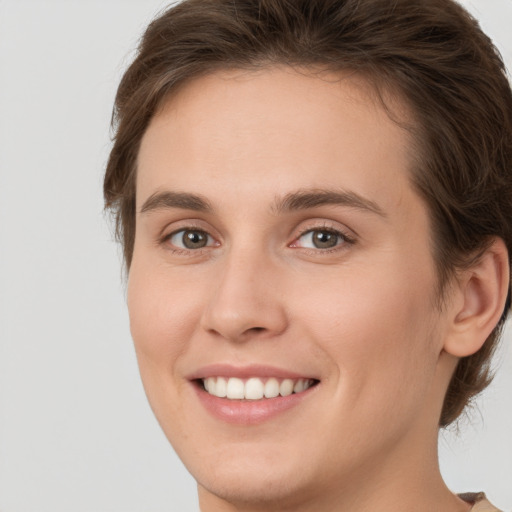 Joyful white young-adult female with short  brown hair and green eyes