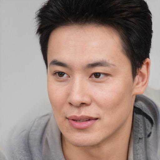 Joyful asian young-adult male with short  brown hair and brown eyes