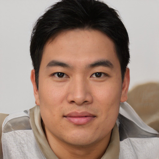 Joyful asian young-adult male with short  brown hair and brown eyes