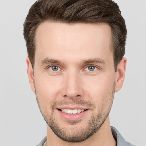 Joyful white young-adult male with short  brown hair and grey eyes