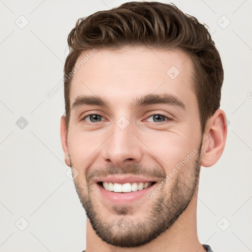 Joyful white young-adult male with short  brown hair and grey eyes