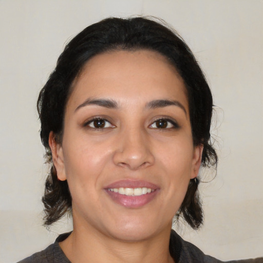 Joyful latino young-adult female with medium  brown hair and brown eyes