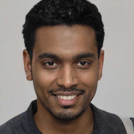 Joyful black young-adult male with short  black hair and brown eyes