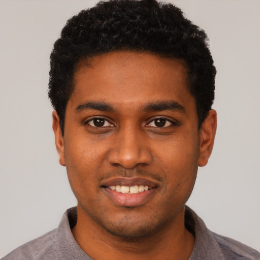 Joyful black young-adult male with short  black hair and brown eyes