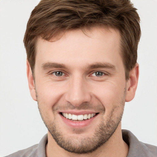 Joyful white young-adult male with short  brown hair and grey eyes