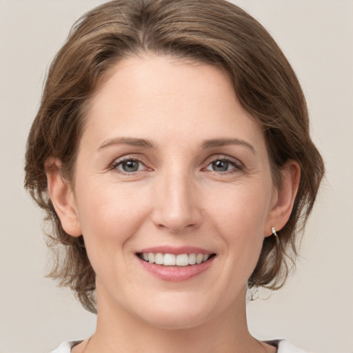 Joyful white young-adult female with medium  brown hair and grey eyes