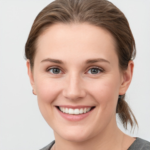 Joyful white young-adult female with medium  brown hair and grey eyes