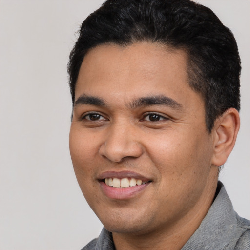 Joyful latino young-adult male with short  black hair and brown eyes