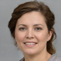 Joyful white young-adult female with medium  brown hair and grey eyes