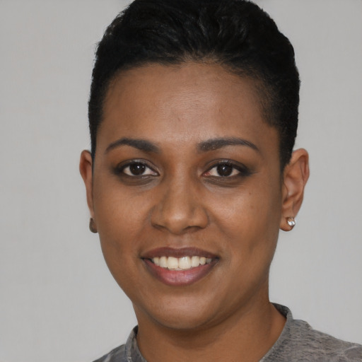 Joyful black young-adult female with short  black hair and brown eyes
