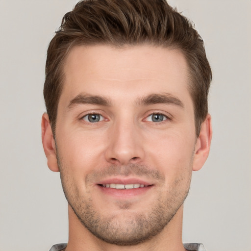 Joyful white young-adult male with short  brown hair and grey eyes