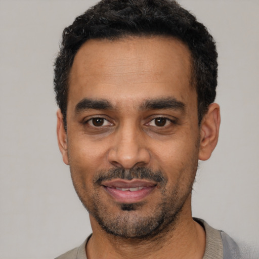 Joyful black young-adult male with short  black hair and brown eyes