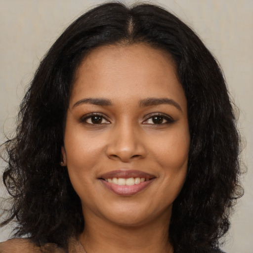 Joyful black young-adult female with long  black hair and brown eyes