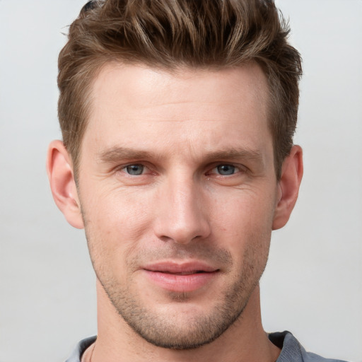 Joyful white young-adult male with short  brown hair and grey eyes