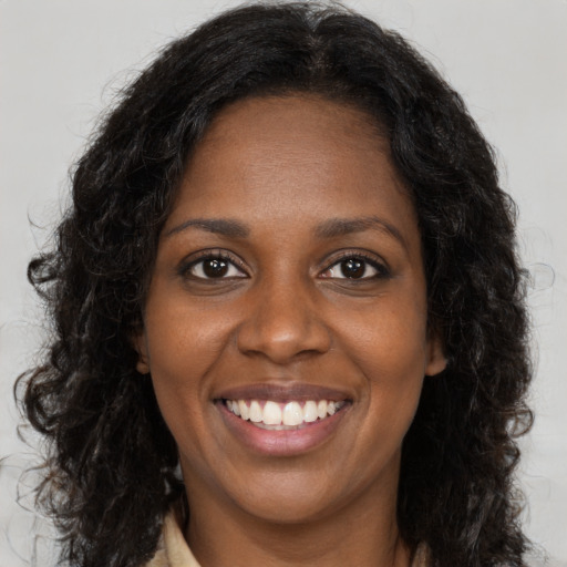 Joyful black young-adult female with long  brown hair and brown eyes