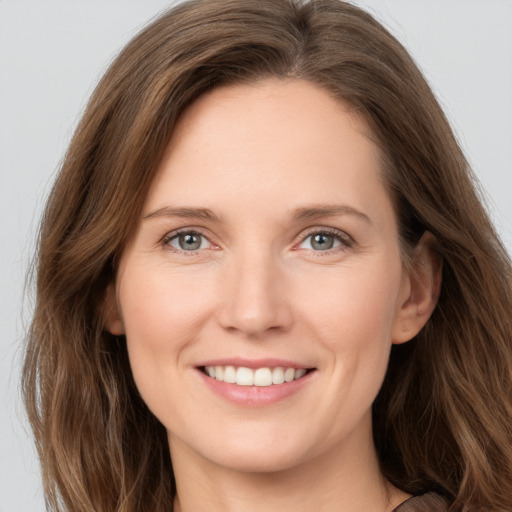 Joyful white young-adult female with long  brown hair and grey eyes