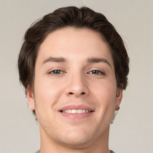 Joyful white young-adult male with short  brown hair and grey eyes