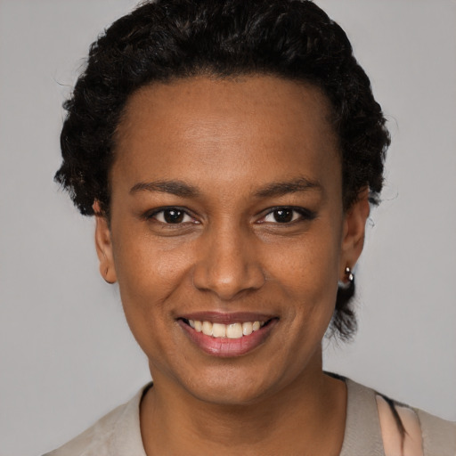 Joyful black young-adult female with short  black hair and brown eyes