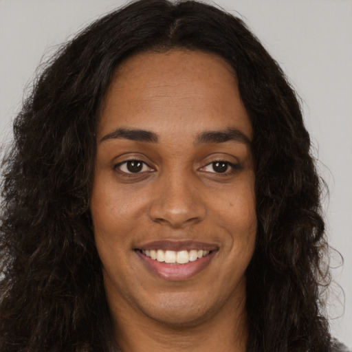 Joyful black young-adult female with long  brown hair and brown eyes