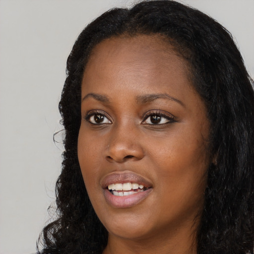 Joyful black young-adult female with long  black hair and brown eyes