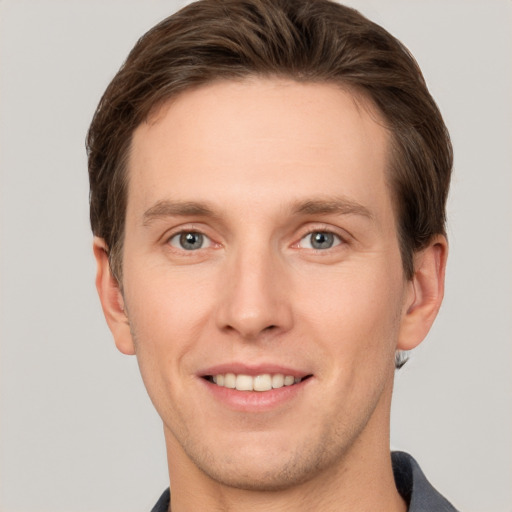 Joyful white young-adult male with short  brown hair and grey eyes